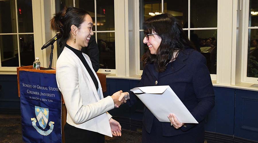 Dean Rosen-Metsch greets a student as she collects her Honor Society certificate.