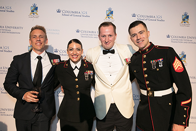 Four decorated veterans pose in front of the step-and-repeat, which displays the logos of the four Military Ball host organizations