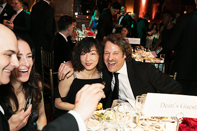 Two guests of the dean take a selfie, while two other guests look on and laugh