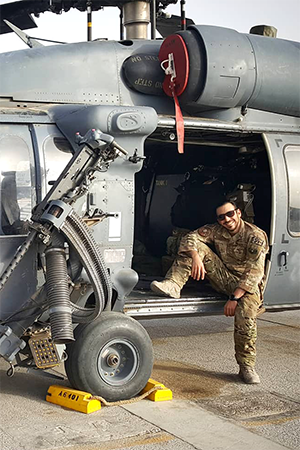GS student Greg Brook sits at the open door of a helicopter, dressed in fatigues