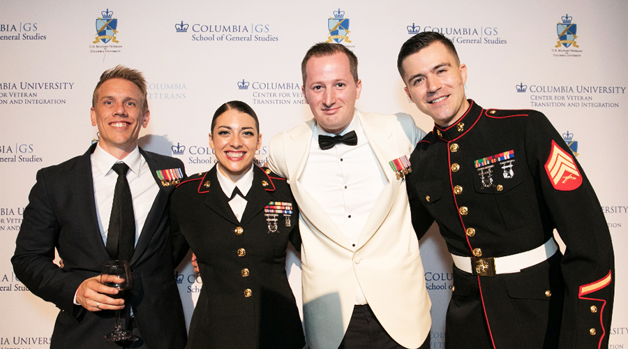 Four veterans pose in front of the step-and-repeat, displaying the logos of the 2019 Military Ball co-hosts