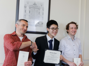 Three students shake hands and pose with their Phi Beta Kappa certificates. 