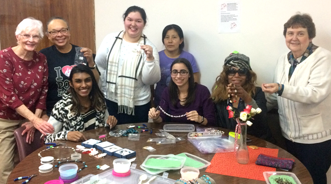 Group of eight students and participants standing behind a table covered in crafting materials