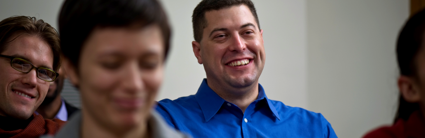 Man in blue shirt laughing in a classroom with other students
